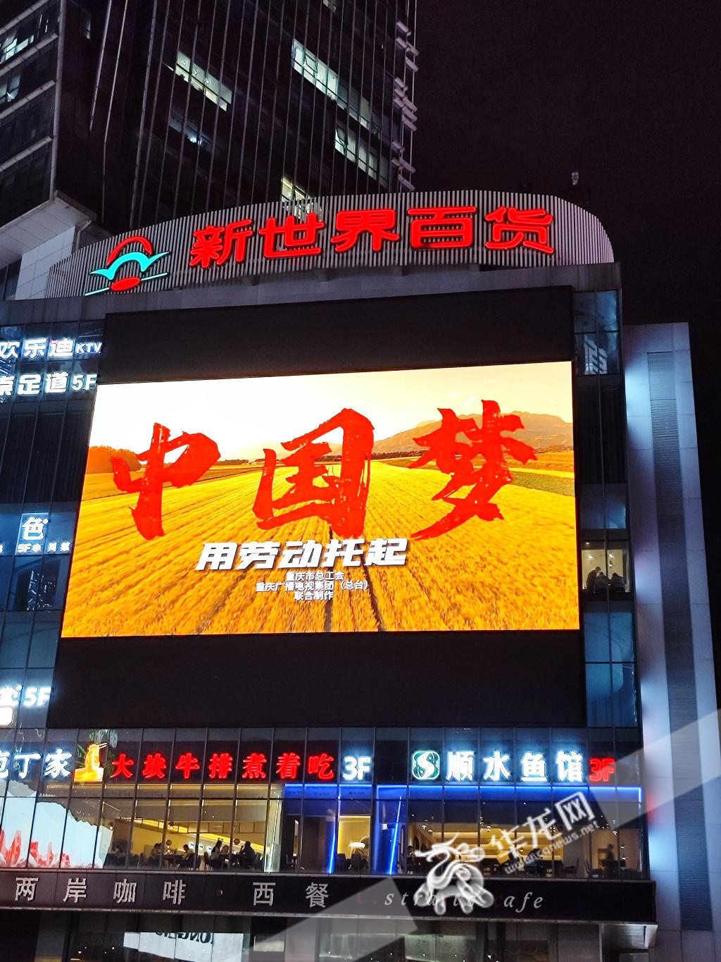 30日晚，观音桥等地标建筑的LED大屏上，滚动播放劳动节节日问候标语、海报和视频，向劳动者致敬。华龙网记者 杨琦摄