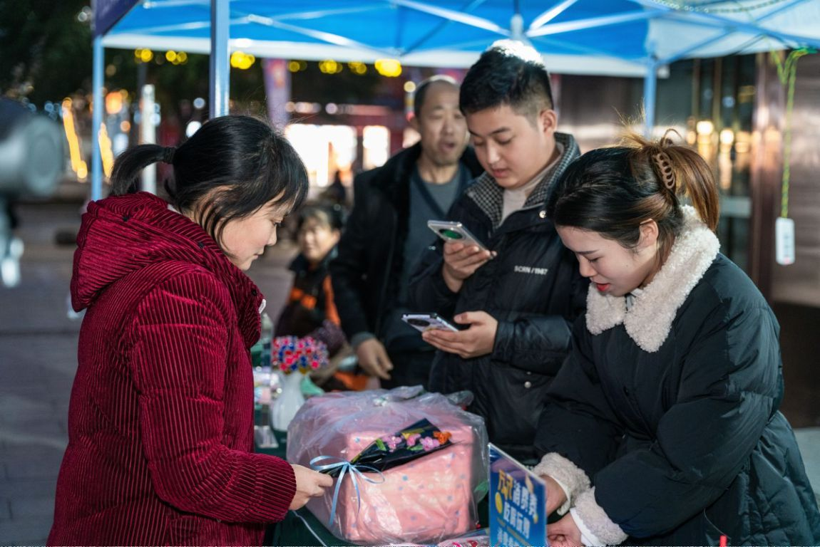 夜市摊位前，顾客扫码领取“渝职聘”平台发放的消费券购物。重庆市人力社保局供图