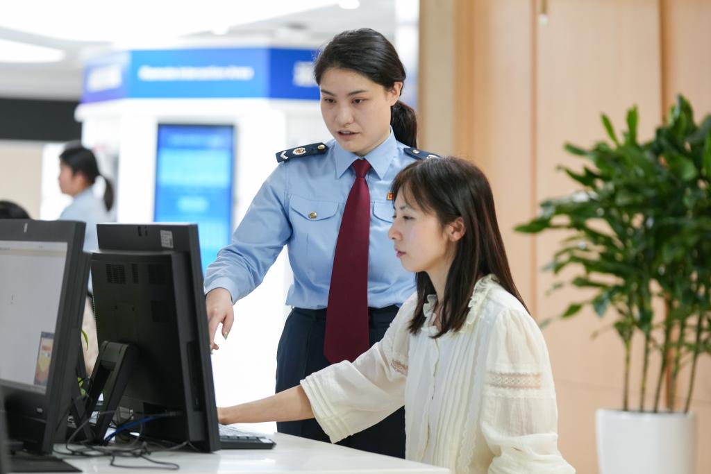 两江新区办税服务厅工作人员辅导纳税人使用电子税务局进行发票申领。重庆市税务局供图