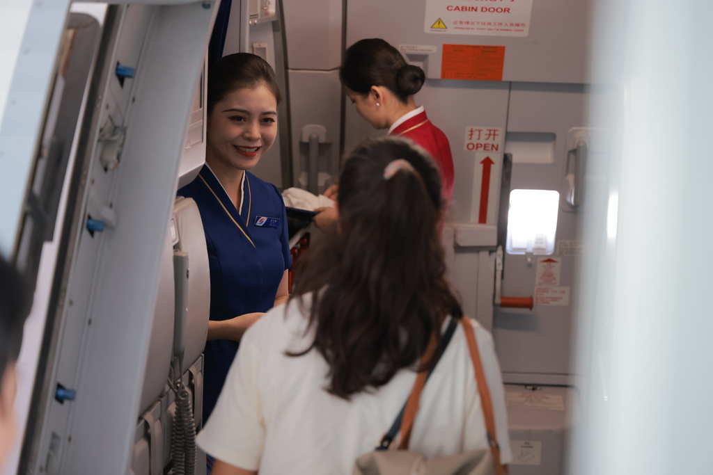 翟艺琳在客舱内迎接旅客。重庆航空供图