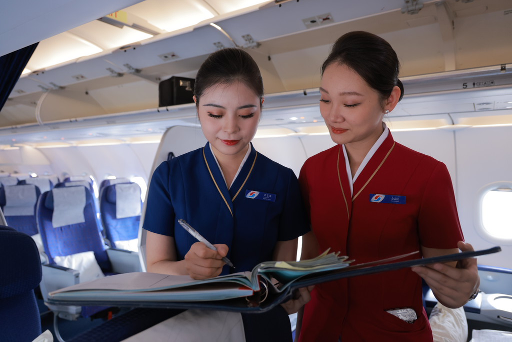翟艺琳向徒弟余孟柯提醒客舱服务注意事项。重庆航空供图