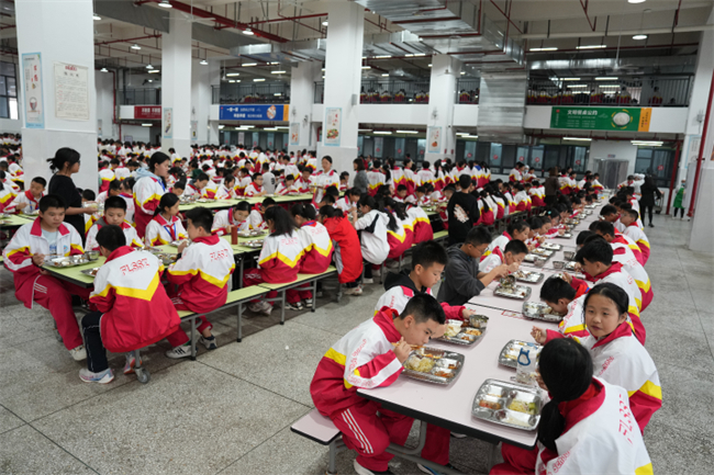 涪州中学的学生中午在学校食堂吃着香喷喷的饭菜。