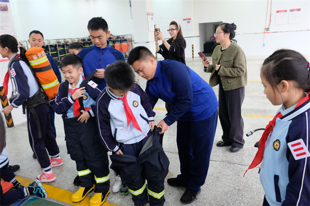 消防员帮助师生穿戴消防救援服。两路街道供图 华龙网发