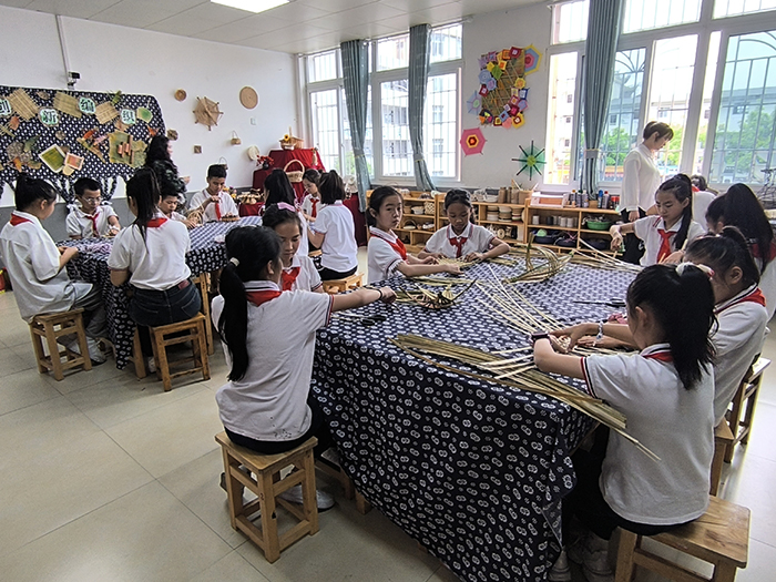 在赶水小学乡村少年宫的手工活动室内，同学们正在用竹条编织手工作品。綦江区委宣传部供图 华龙网发