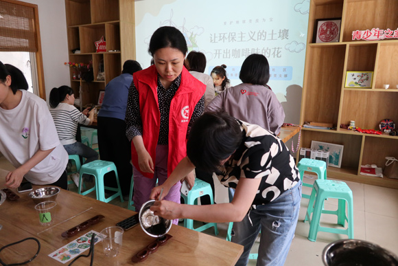 现场志愿者耐心指导居民制作咖啡渣手工皂。龙溪街道办事处供图 华龙网发