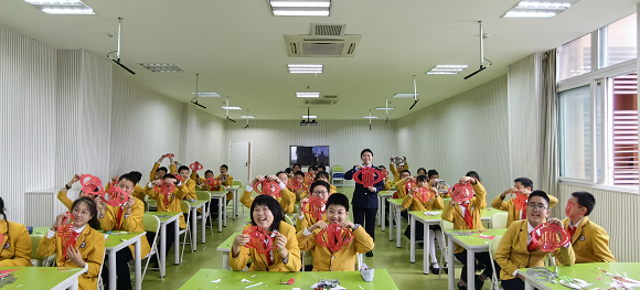 在大足区迪涛学校，税务人员和同学们与“税徽”剪纸合影留念。孟祥菲 摄