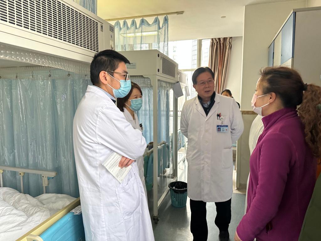 刘林教授（左二）和王利教授（左三）在病房和患者家属交流。医院供图