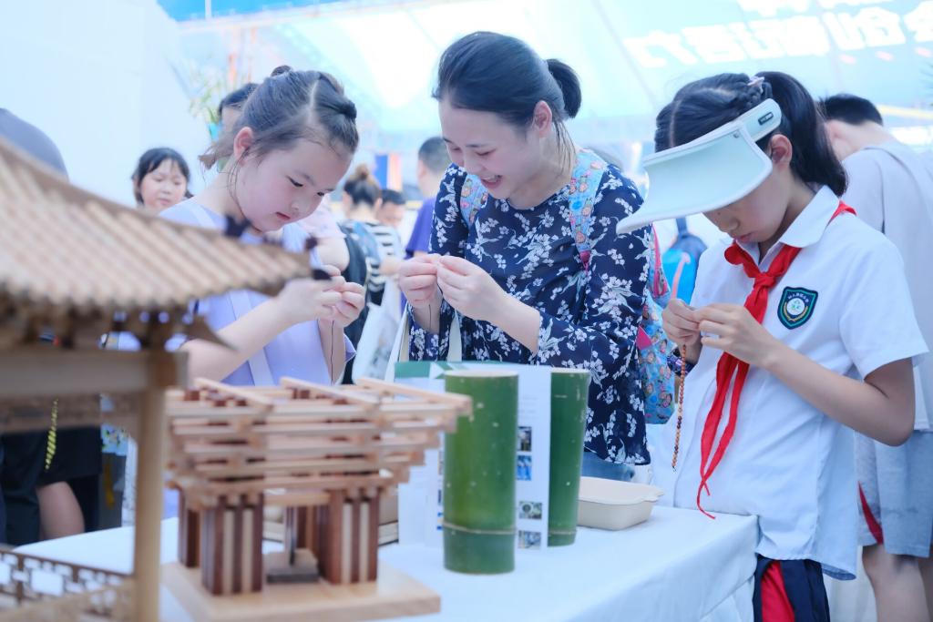 小朋友正在利用楠木珠制作手工艺品。 记者 欧武夷 摄