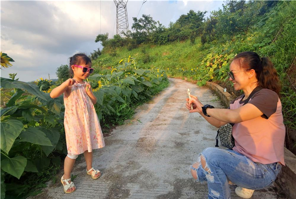 在归原果寨家庭农场内，游客为孩子拍照留念。