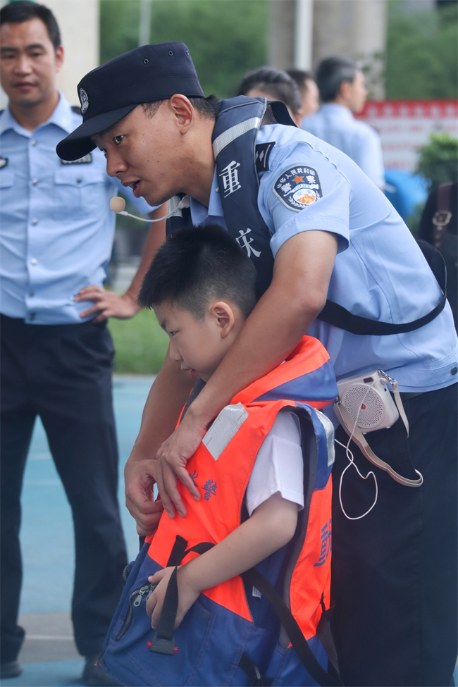 朱力波警官正在教小朋友如何正确穿戴救生衣。实习生 吉妙 摄