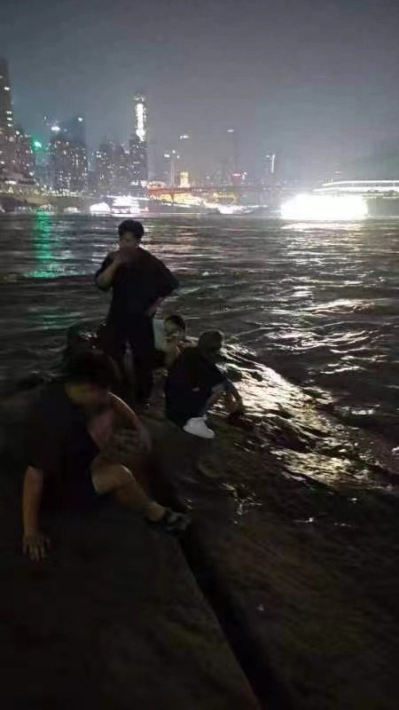 The man in white who fell into the water was rescued and rested on the rocks with his companions. (Photo provided by a netizen)