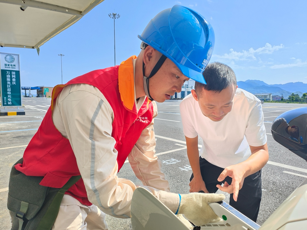 The staff of State Grid Qijiang Power Supply Company assisted drivers charge new energy vehicles with ultra-fast charging piles at the charging station in Wansheng Service Center