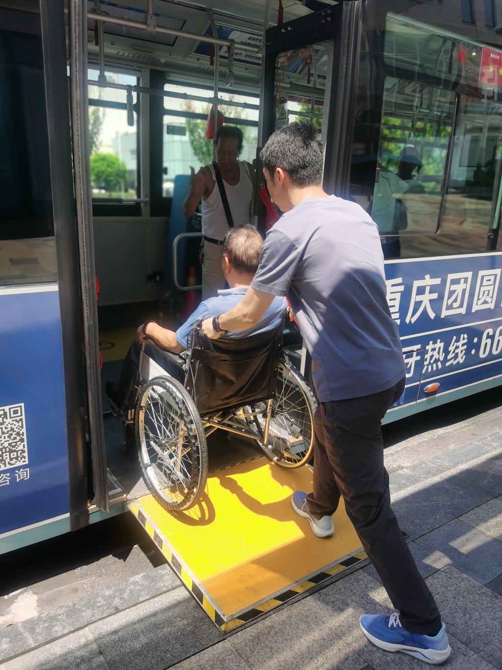彭庆华坐在轮椅上，可以很方便地通过连接板乘坐公交。 渝中区残联供图