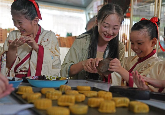 孩子们在老师（中）的指导下体验传统手工月饼制作。新华社记者 万象 摄