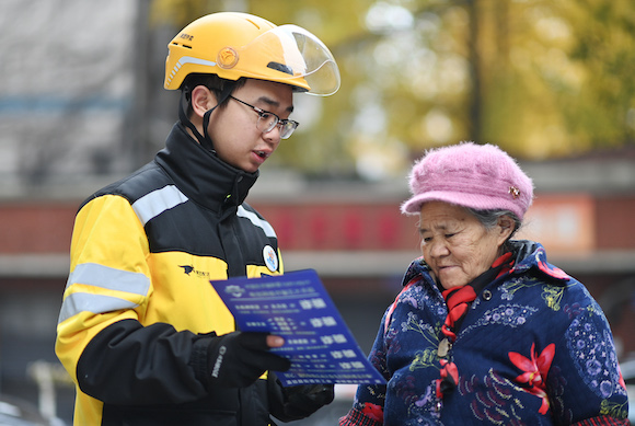 沙坪壩區(qū)“紅巖騎手”志愿服務(wù)者向老人們發(fā)放防電詐宣傳單。沙坪壩區(qū)融媒體中心供圖