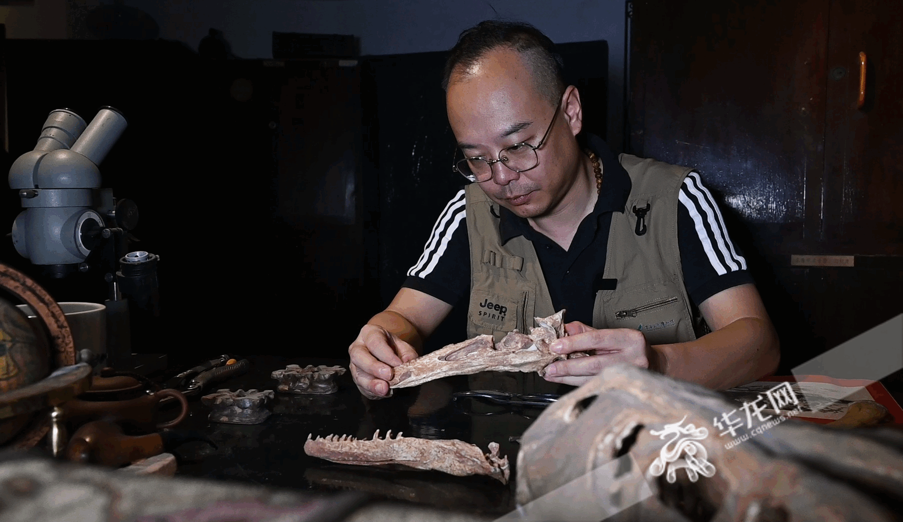 重庆自然博物馆恐龙化石修复实验室内，修复师曾焱垚正在观察一块恐龙化石