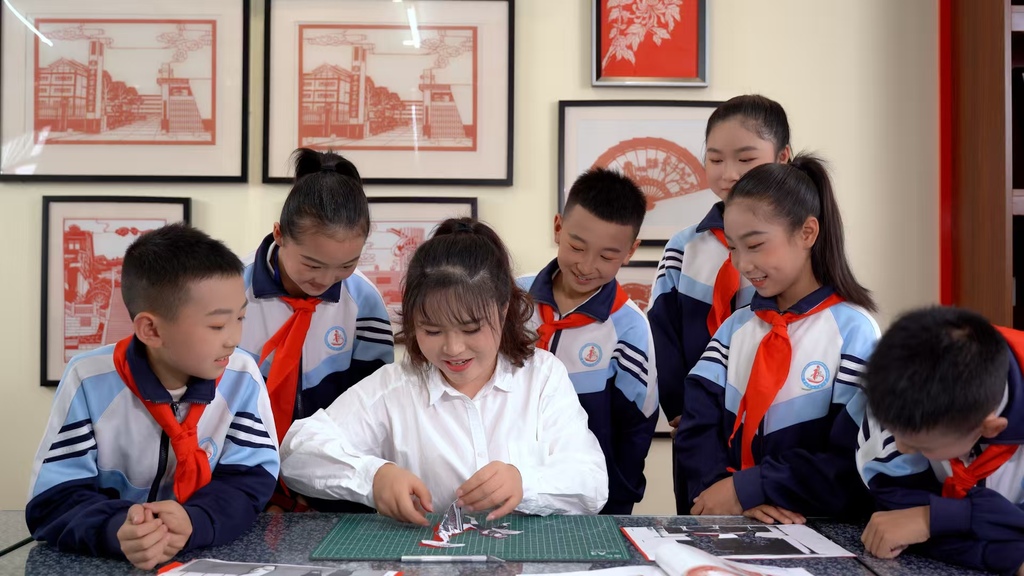 孩子们正在围着老师学习剪纸。受访者供图