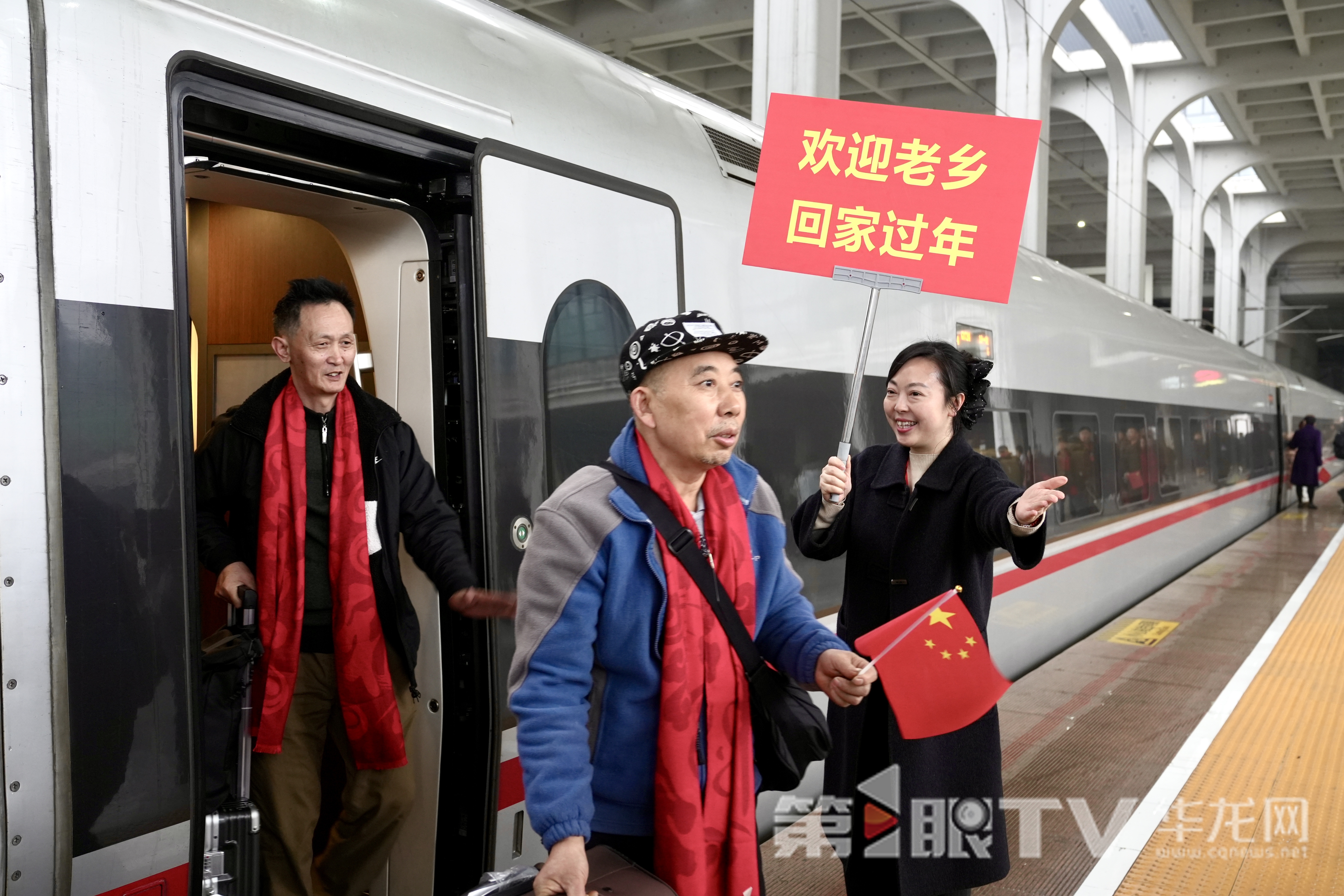 工作人員手舉歡迎牌迎接外出務工人員下車。 第1眼TV-華龍網記者 劉釗 攝