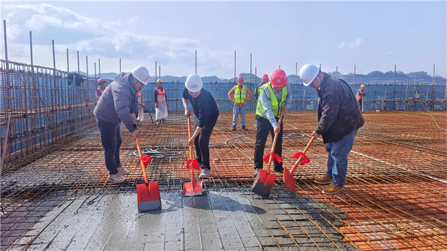 梁平区冷链物流园建设项目（三期）1号楼楼顶，项目（三期）相关负责人及工作人员手持铁铲在现场平整混凝土。梁平区融媒体中心供图