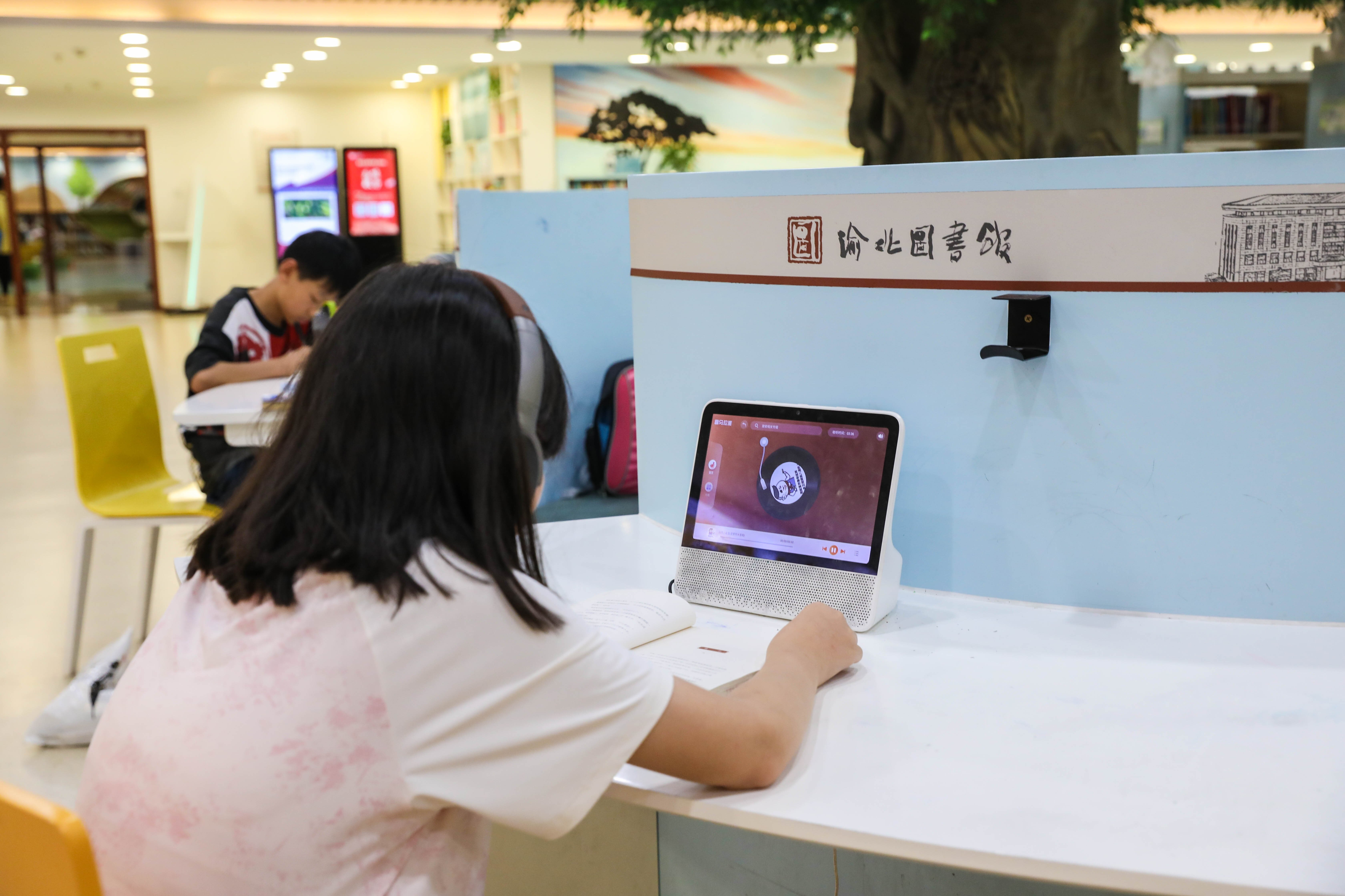 渝北图书馆数字体验区读者借助智能设备正在听书