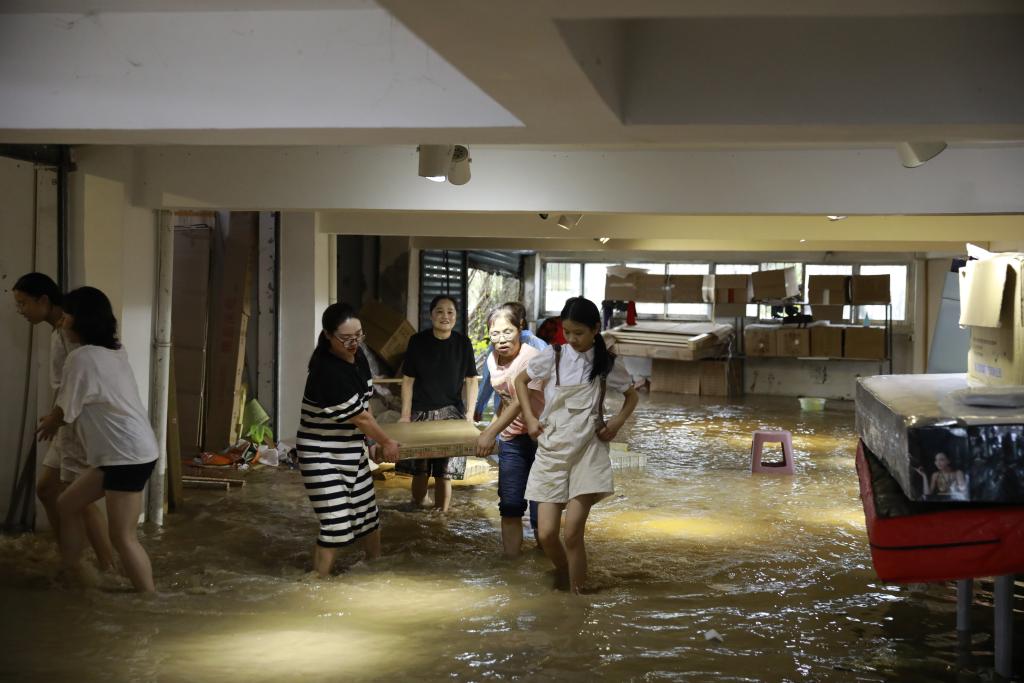 7月11日，洪水涌入礼让镇场镇某家具厂，工人和附近居民一起紧急转运财产。记者 熊伟 摄