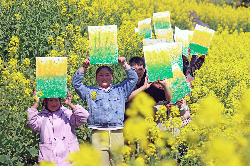 2025年3月24日，重庆市彭水苗族土家族自治县双龙乡小学校的孩子们，正在展示自己走进油菜花田里的写生作品。
