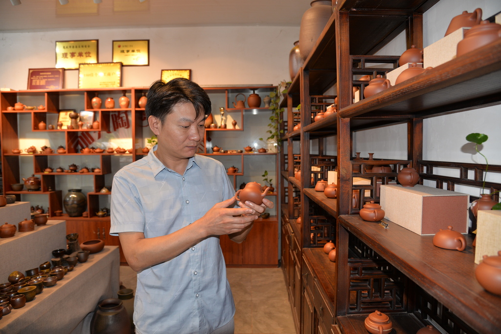 李加兴在工作室查看陶艺作品