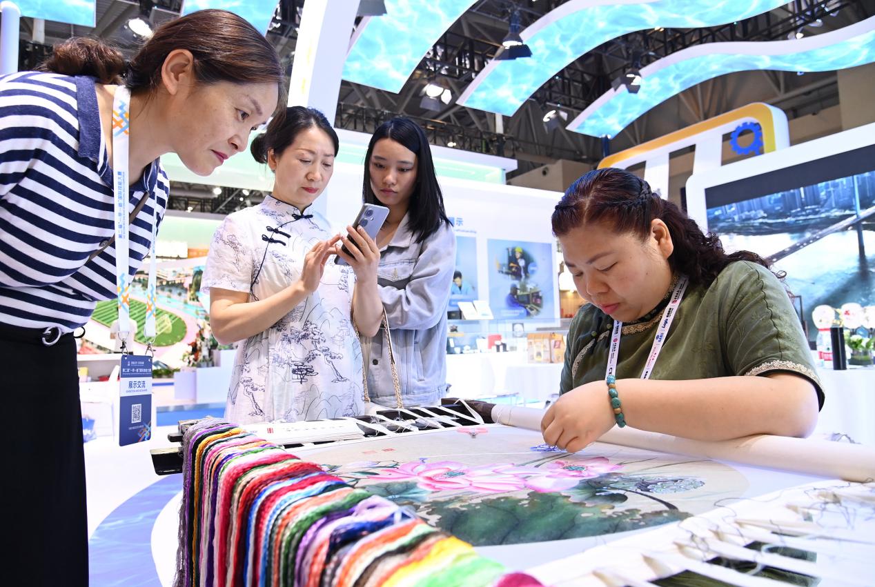 12-6月25日，重庆国际博览中心N5馆，观众在沙坪坝区展厅体验非遗蜀绣。