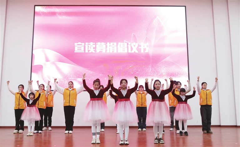 图为爱心妈妈及儿童宣读募捐倡议书。