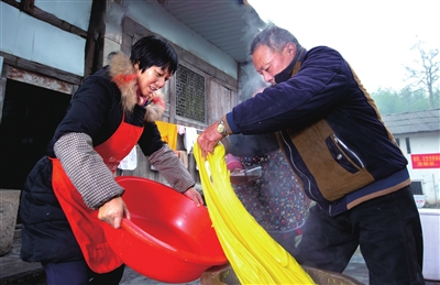 虎城镇集中村一组,村民唐大均从石碓臼中取出打好的糯米,准备制作黄粑粑。通讯员 蒋巧龙 摄 虎城镇集中村一组,村民唐大均从石碓臼中取出打好的糯米,准备制作黄粑粑。通讯员 蒋巧龙 摄