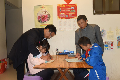 帮扶责任人何亚峰（左）罗洪俸 (右)在指导小孩做作业。特约通讯员　隆太良　摄