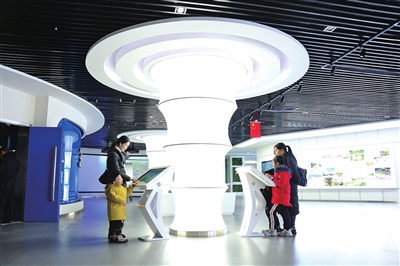 梁平规划展览馆，市民带着孩子在体验智能交通等互动游戏。
