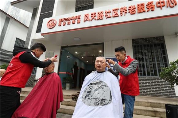 凤天路社区养老服务中心门前，志愿者正在为老人理发。沙坪坝区委宣传部供图 华龙网发