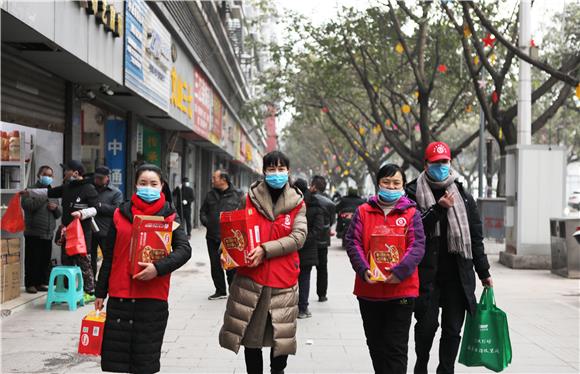 巾帼志愿者抱着腊八粥走在街头。通讯员 陈仕川 摄