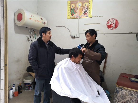 王仕刚在理发店接受华龙网—新重庆客户端记者采访。简梦 摄