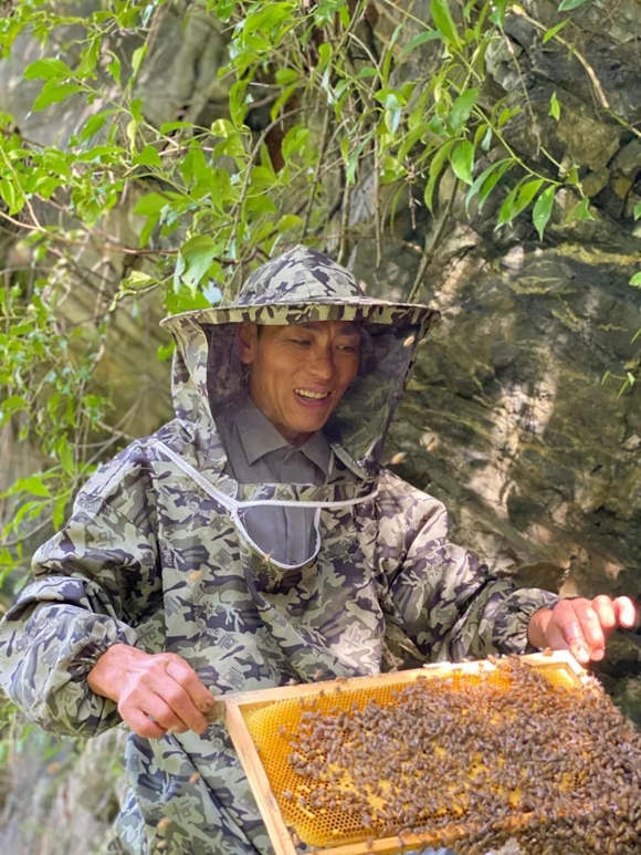 张山民取自家蜂蜜。鸡鸣乡政府供图 华龙网发