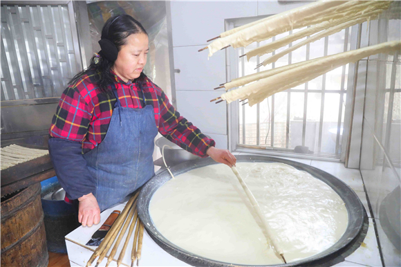 1月27日，梁平区礼让镇同河村8组，村民用竹棍在铁锅内裹豆筋。刘辉 摄(1)