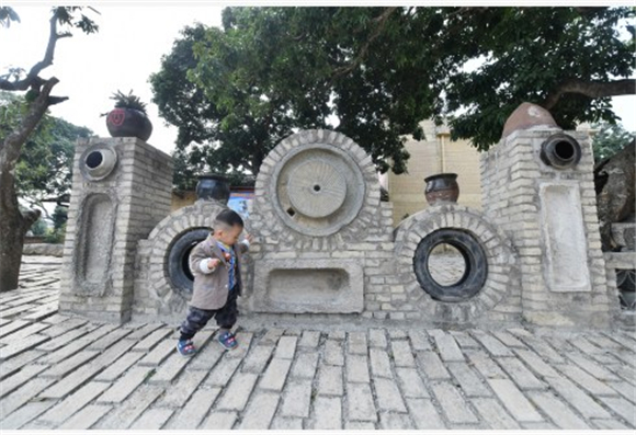 在广西钦州市浦北县北通镇清湖村刘屋自然村，小朋友在废旧轮胎、石磨等打造的景观前玩耍。新华社记者 黄孝邦 摄