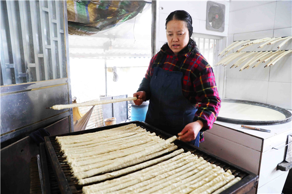 1月27日，梁平区礼让镇同河村8组，村民在把裹好的豆筋放到木箱上。刘辉 摄