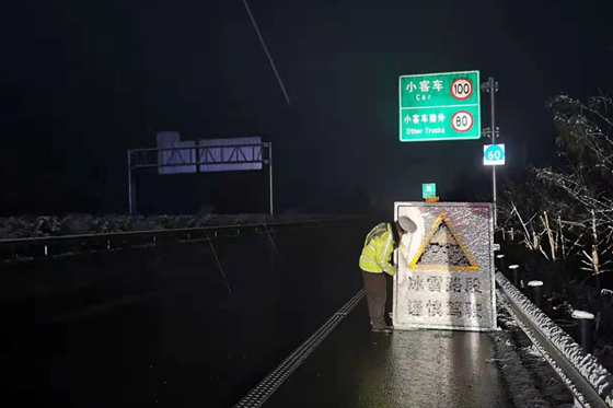 张南高速铁门路段，高速执法人员正清除放置的雨雪天气警示牌上的积雪。通讯员 兰江 摄
