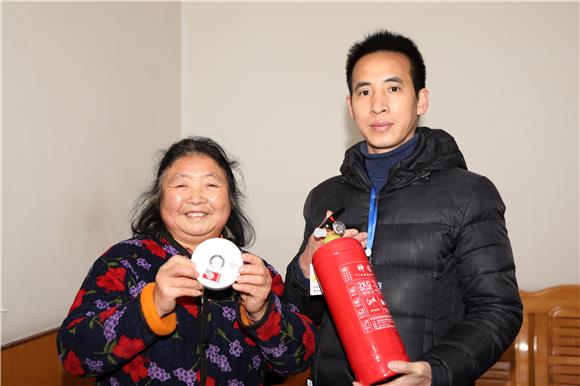 70岁的范桂芳展示街道赠送的干粉灭火器和独立式感烟探测器 通讯员 陈仕川 摄