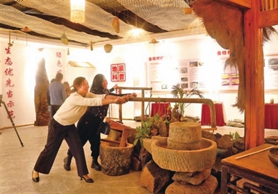 七星镇金柱村村情陈列馆，游客在体验传统推石磨工艺。通讯员 向成国 摄