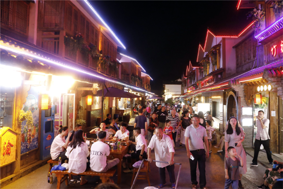 竹山镇猎神三巷，游客在品尝美食。通讯员 向成国 摄