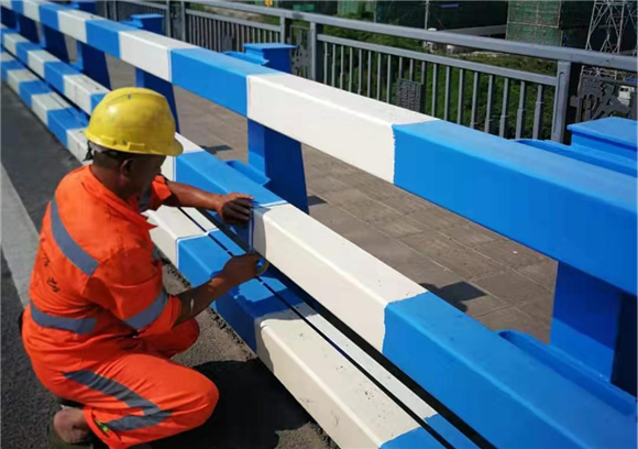 市政设施维护管理者正在测量蓝色涂漆面积是否符合标准。市政设施运行保障中心供图 华龙网发