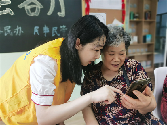 志愿者正在教老年人使用智能手机。南岸区民政局供图  华龙网发