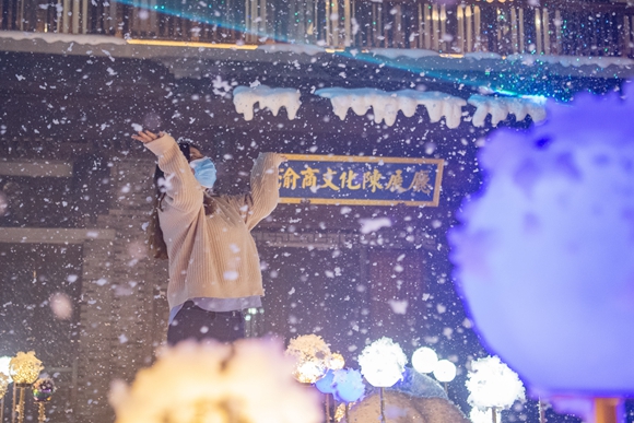 游客在重庆弹子石老街王家大院景点体验极光秀和人工雪。