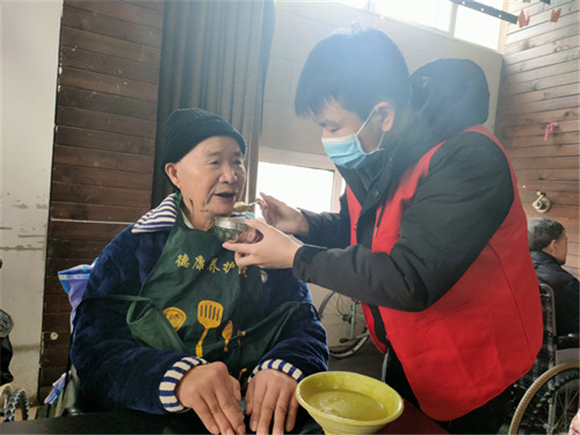 志愿者为老人喂饭。通讯员  赵爱红   摄