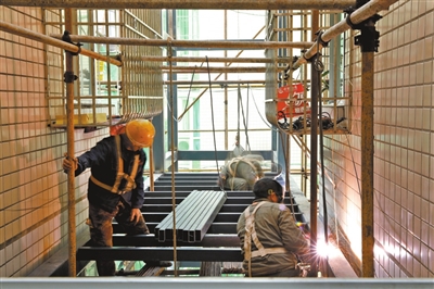位于梁山街道鲁班路的玉龙庭院小区电梯加装现场，工人在焊接钢结构。通讯员 何建军 向成国 供图