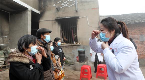 医务人员教村民口罩的正确戴法。特约通讯员 陈仕川 摄