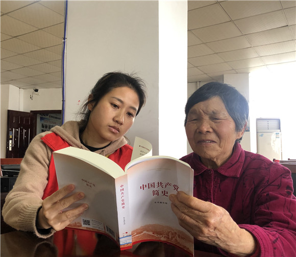 农家书屋工作人员为老年人提供阅读指导。（张浩 摄）
